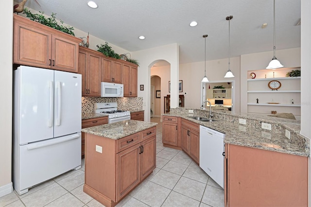 kitchen with sink, light stone counters, hanging light fixtures, kitchen peninsula, and white appliances