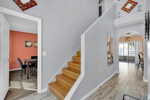 stairway featuring wood-type flooring and a towering ceiling