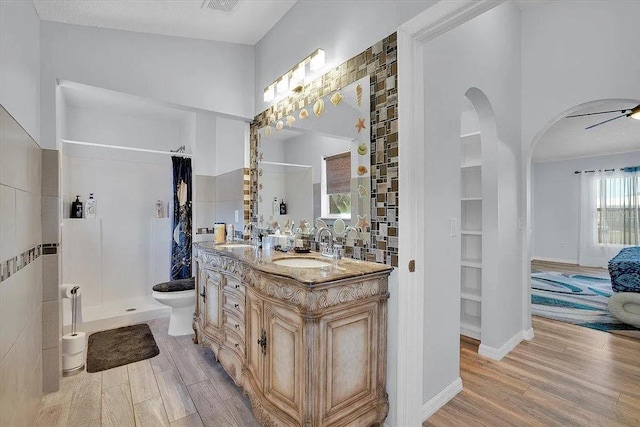 bathroom with hardwood / wood-style flooring, vanity, toilet, and walk in shower