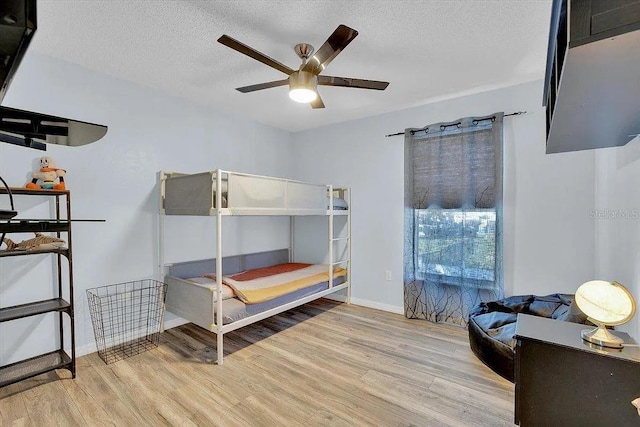 bedroom featuring ceiling fan, light hardwood / wood-style flooring, and a textured ceiling