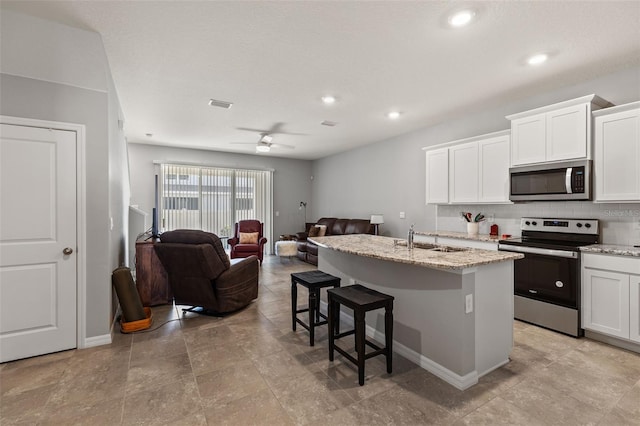 kitchen featuring a kitchen island with sink, sink, stainless steel appliances, and white cabinets