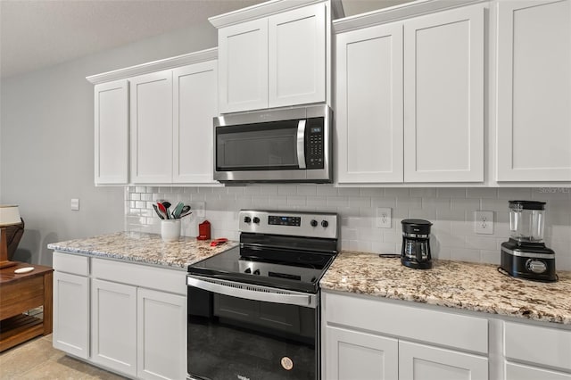 kitchen featuring white cabinetry, backsplash, light stone counters, and appliances with stainless steel finishes