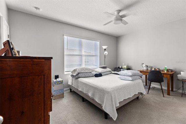 bedroom with ceiling fan, light carpet, and a textured ceiling