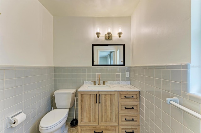 bathroom with vanity, toilet, and tile walls