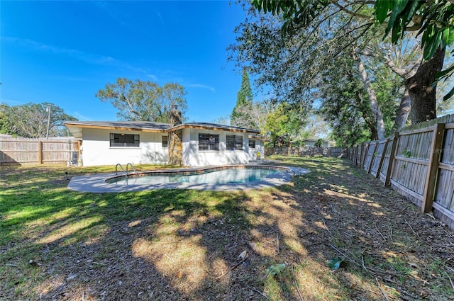 rear view of house with a fenced in pool and a yard