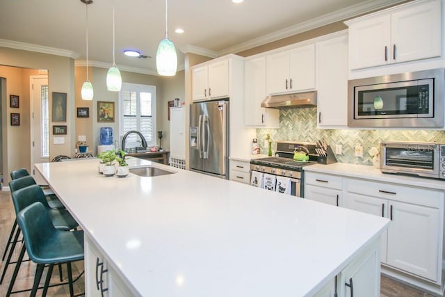 kitchen with appliances with stainless steel finishes, a breakfast bar, a kitchen island with sink, and white cabinets