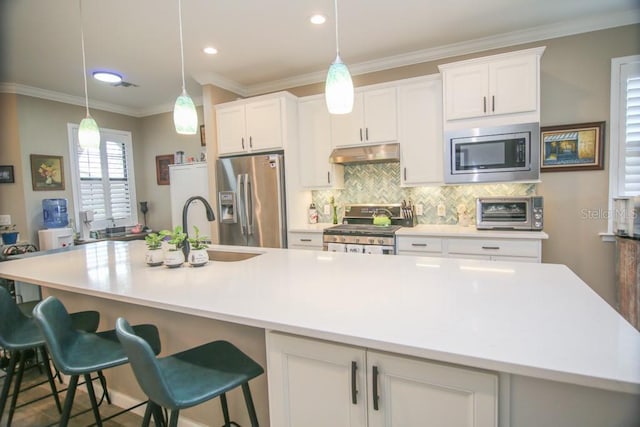 kitchen featuring stainless steel appliances, white cabinetry, sink, and a large island with sink