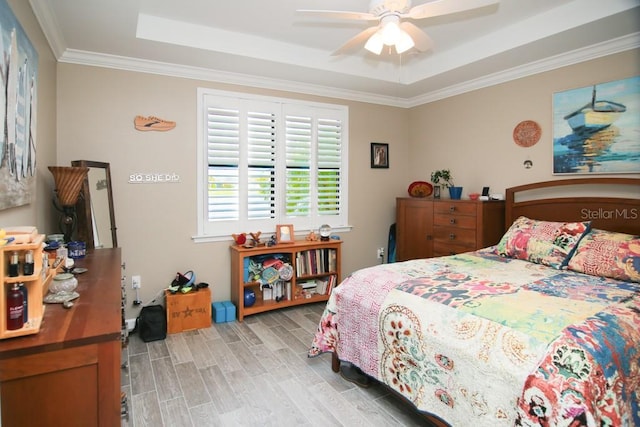 bedroom featuring crown molding, a tray ceiling, light hardwood / wood-style flooring, and ceiling fan