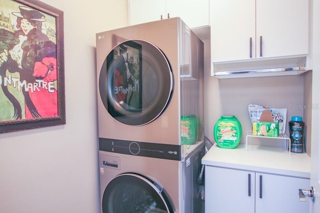 laundry area with stacked washer / drying machine and cabinets