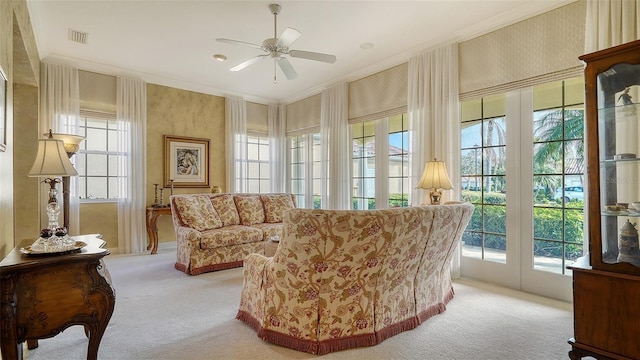 living area with crown molding, light colored carpet, and ceiling fan