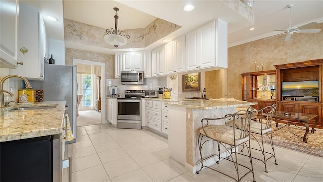 kitchen with pendant lighting, white cabinetry, sink, stainless steel appliances, and crown molding