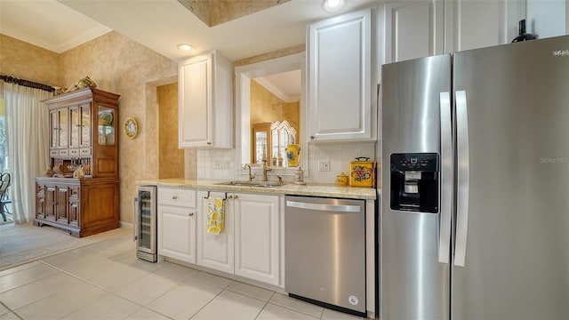 kitchen with sink, appliances with stainless steel finishes, wine cooler, light stone counters, and white cabinets