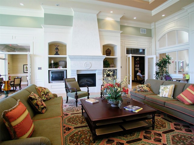 living room featuring a large fireplace, ornamental molding, and built in features