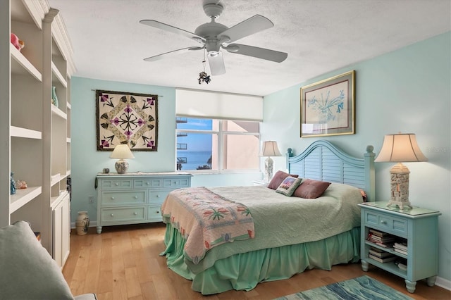 bedroom featuring a textured ceiling, light hardwood / wood-style flooring, and ceiling fan