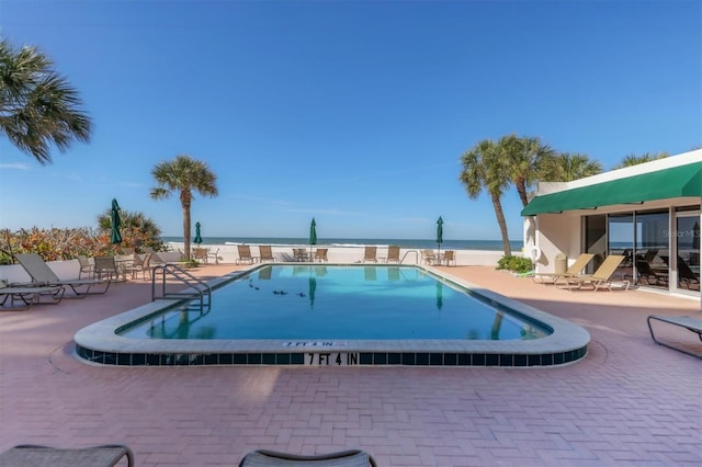 view of swimming pool featuring a patio and a water view