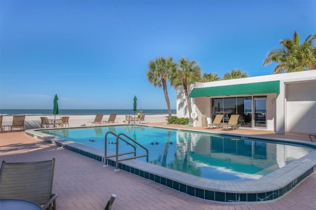 view of swimming pool featuring a patio and a water view