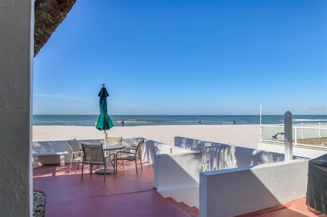 view of patio / terrace with a water view and a beach view