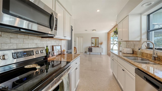 kitchen with light stone counters, appliances with stainless steel finishes, sink, and white cabinets