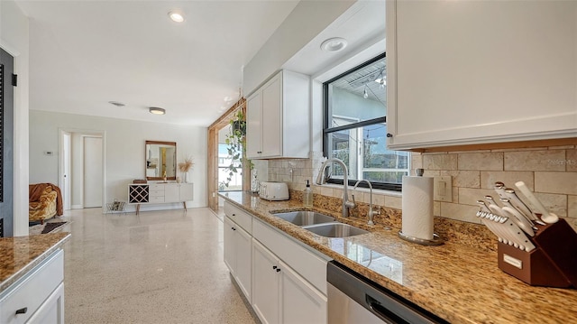 kitchen featuring light stone counters, sink, a healthy amount of sunlight, and white cabinets