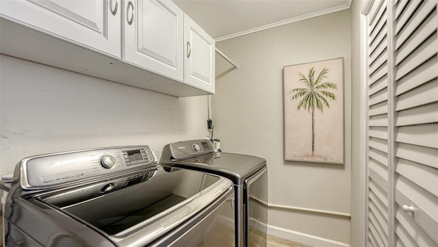 clothes washing area with cabinets, ornamental molding, and washer and clothes dryer