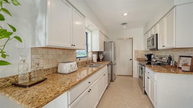 kitchen with tasteful backsplash, white cabinetry, sink, light stone counters, and stainless steel appliances