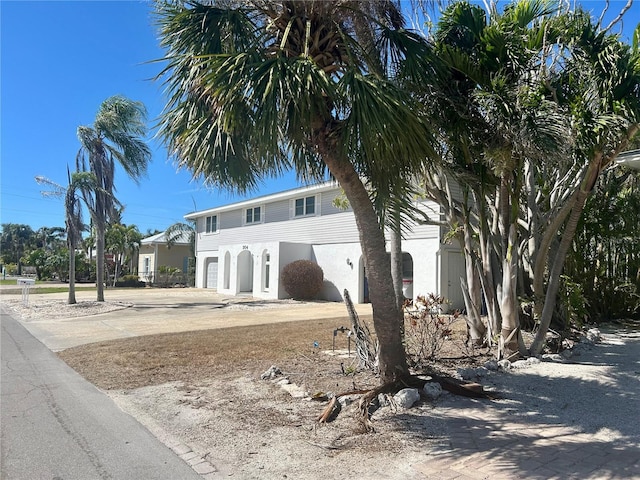 view of front of property with concrete driveway, an attached garage, and stucco siding