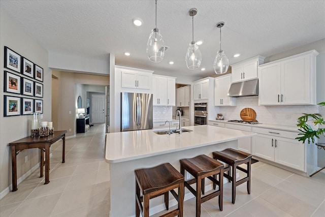 kitchen featuring a breakfast bar, sink, white cabinetry, hanging light fixtures, and appliances with stainless steel finishes