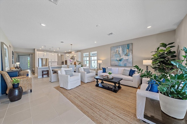 living room with a textured ceiling, a chandelier, and light tile patterned flooring