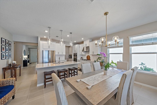 tiled dining room featuring a chandelier, sink, and a textured ceiling