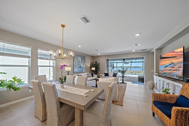 dining space featuring light tile patterned floors, a textured ceiling, and an inviting chandelier