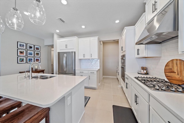 kitchen with appliances with stainless steel finishes, an island with sink, sink, a breakfast bar area, and hanging light fixtures