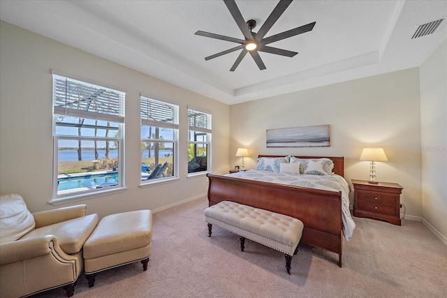 carpeted bedroom with a raised ceiling and ceiling fan