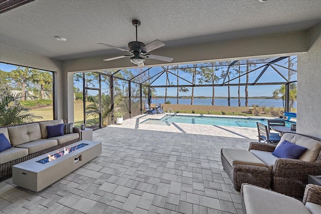 view of patio with a water view, an outdoor living space with a fire pit, and a lanai