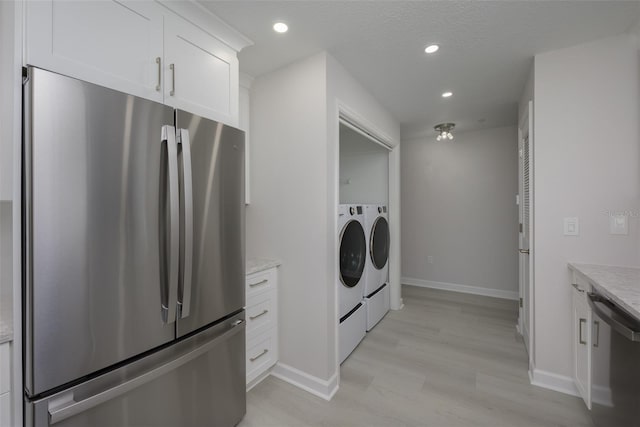 laundry area with washing machine and clothes dryer, light hardwood / wood-style flooring, and a textured ceiling