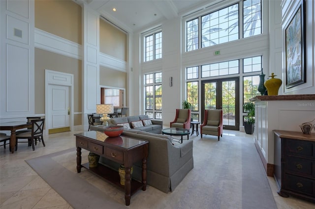 living room with beamed ceiling, a towering ceiling, and french doors