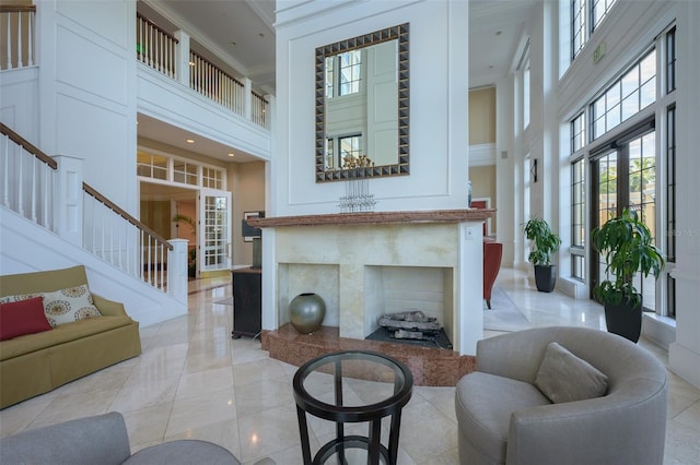 living room featuring crown molding, a towering ceiling, and a fireplace