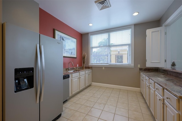 kitchen with stainless steel appliances, sink, light tile patterned floors, and cream cabinetry