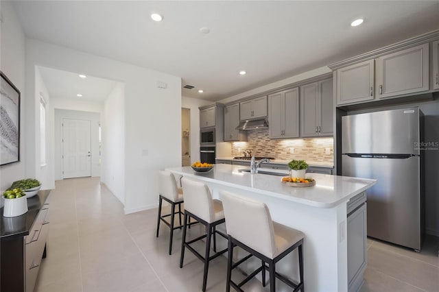 kitchen featuring stainless steel appliances, a kitchen island with sink, and gray cabinetry