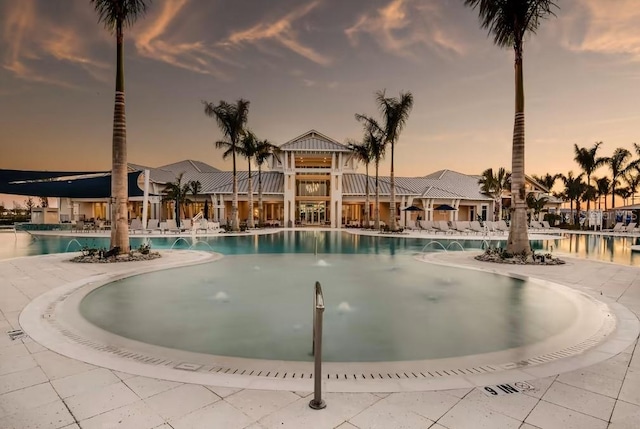 pool at dusk featuring pool water feature