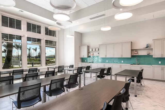 dining space with sink, a raised ceiling, light parquet flooring, and a high ceiling