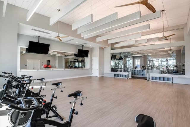 exercise room with ceiling fan, hardwood / wood-style floors, and a high ceiling