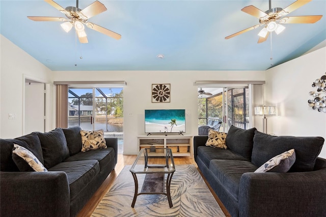 living room featuring ceiling fan, vaulted ceiling, and light hardwood / wood-style flooring