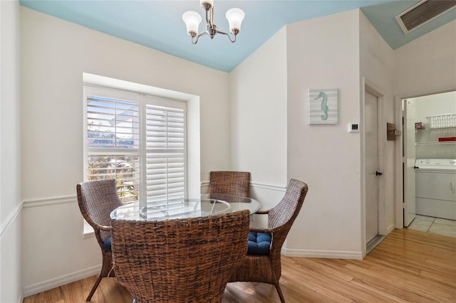 dining area with washer / clothes dryer, a chandelier, and light wood-type flooring