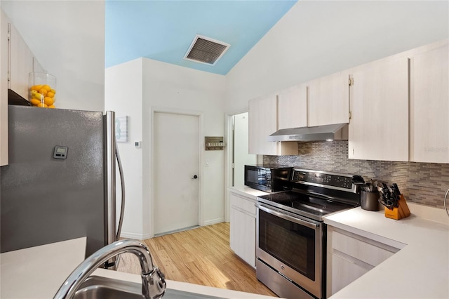 kitchen featuring lofted ceiling, decorative backsplash, light hardwood / wood-style flooring, and appliances with stainless steel finishes