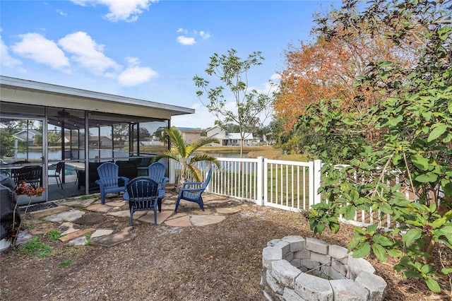 view of yard featuring a patio area, a sunroom, a water view, and an outdoor fire pit