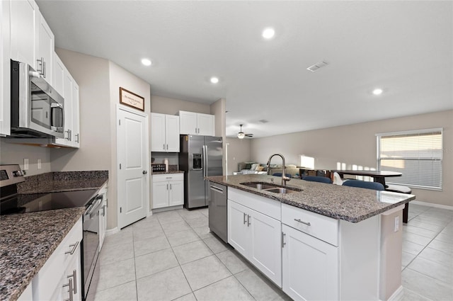 kitchen with a sink, visible vents, white cabinetry, appliances with stainless steel finishes, and a center island with sink