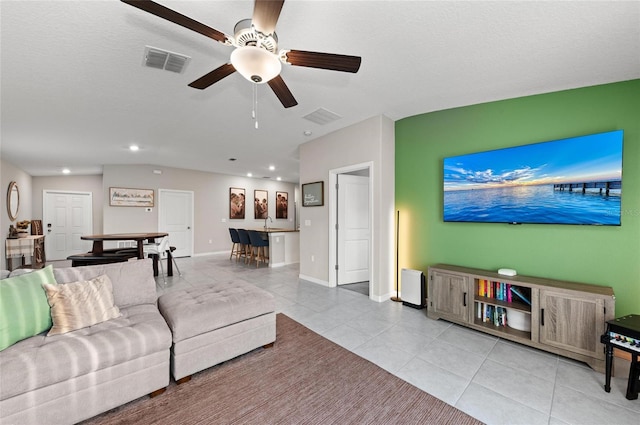 living room with light tile patterned floors, baseboards, visible vents, and a ceiling fan