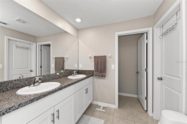 bathroom with double vanity, a sink, visible vents, and tile patterned floors