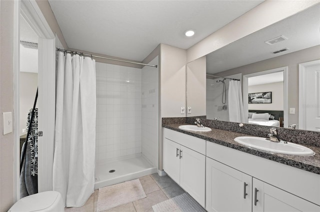 ensuite bathroom featuring visible vents, tiled shower, a sink, and tile patterned floors