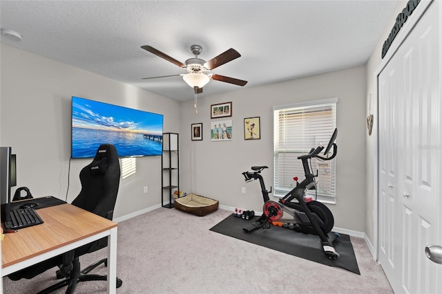 carpeted office space featuring a textured ceiling, ceiling fan, and baseboards